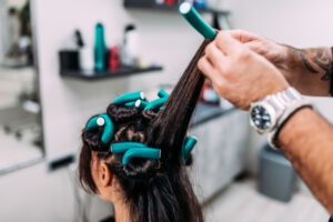 Haidresser making curly hairstyle to a client.
